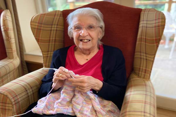 A Heathfield resident sits knitting in a comfortable chair