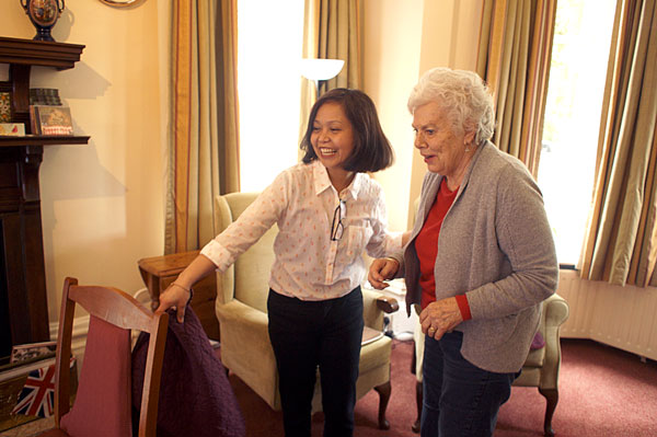 Marjorie, Heathfield's manager, guids a resident across the room